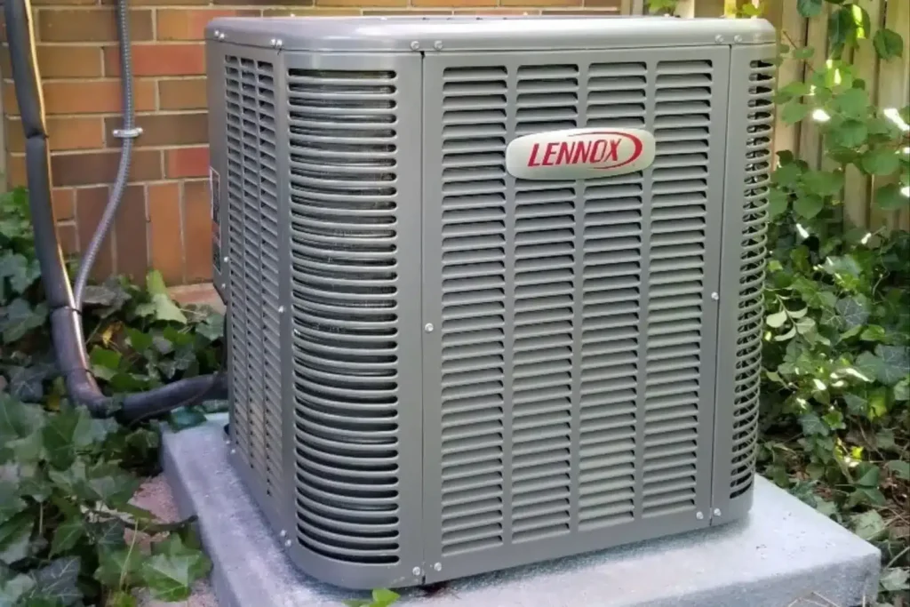 Lennox outdoor central AC condenser on a concrete pad beside a brick wall with ivy